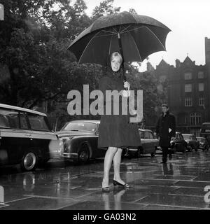 Catherine Deneuve, attrice francese che usa un ombrello mentre ha lasciato il suo hotel di Londra per andare a lavorare al film Repulsion. Foto Stock