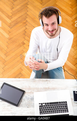 Un giovane uomo che ascolta musica sul suo laptop computer. Foto Stock