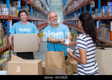 Donna dà alcuni beni di volontariato Foto Stock