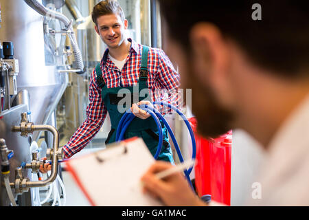 Lavoratori di manutenzione esaminando brewery macchina Foto Stock