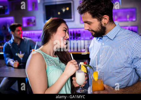 Sorridente amici interagire gli uni con gli altri al bancone mentre avente cocktail Foto Stock