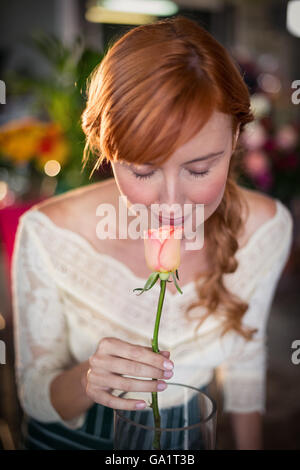 Fiorista femmina odorare un fiore rosa Foto Stock