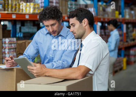 Ritratto di gestori stanno lavorando con una pastiglia nel mezzo di scatole di cartone Foto Stock