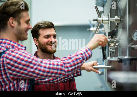 Lavoratori di manutenzione esaminando brewery macchina Foto Stock