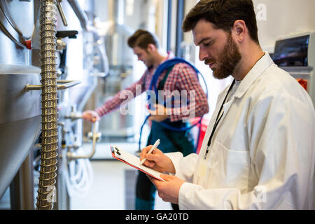 Lavoratori di manutenzione esaminando brewery macchina Foto Stock