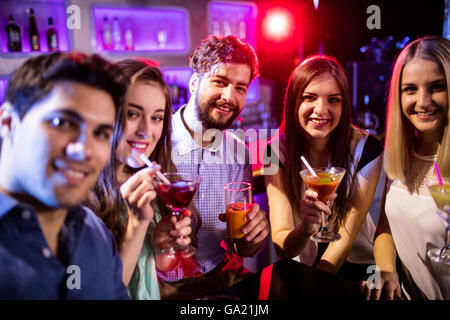 Gruppo di amici avente cocktail al bancone bar Foto Stock