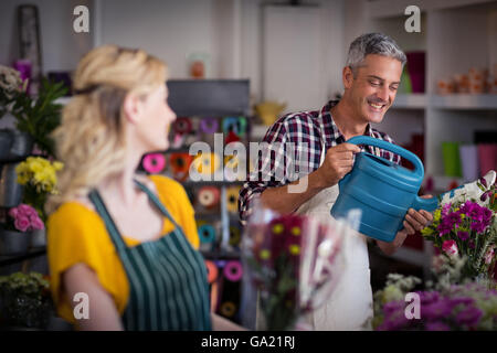 Sorridente fioraio fiori di irrigazione Foto Stock