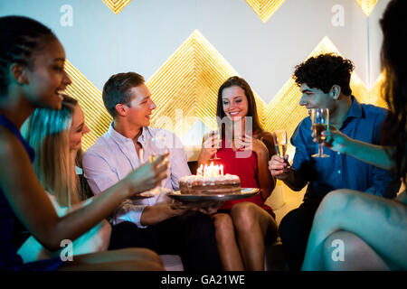 Gruppo di amici sorridente avente un bicchiere di champagne mentre festeggia il compleanno
