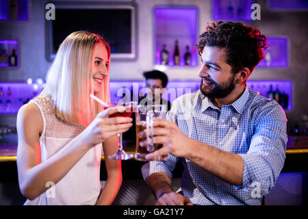 Sorridente amici cocktail di tostatura e la birra di vetro al bancone bar Foto Stock