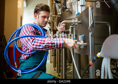 Lavoratori di manutenzione esaminando brewery macchina Foto Stock