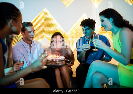 Gruppo di amici sorridente avente un bicchiere di champagne mentre festeggia il compleanno Foto Stock