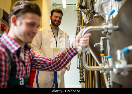 Lavoratori di manutenzione esaminando brewery macchina Foto Stock