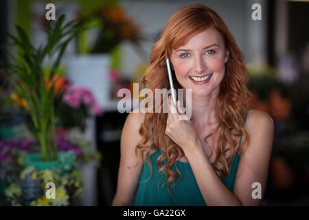 Fiorista femmina parlando al telefono cellulare in negozio di fiori Foto Stock