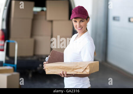 Ritratto di donna di erogazione è in possesso di una scatola di cartone e sorridente per la fotocamera Foto Stock