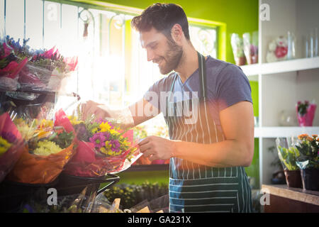 Fioraio maschio disponendo bouquet di fiori negozio di fiori Foto Stock