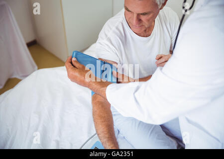 L'infermiera la misurazione della pressione del sangue di un uomo anziano Foto Stock