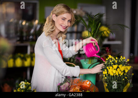 Femmina felice fioraio fiori di irrigazione Foto Stock