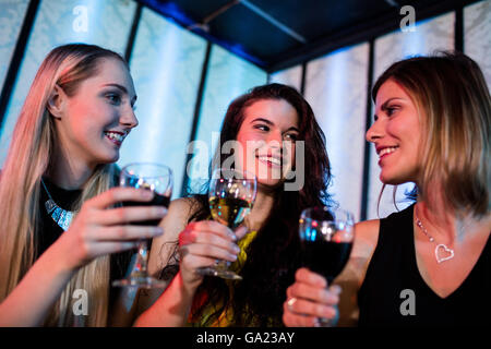 Sorridente amici godendo mentre avente il vino Foto Stock