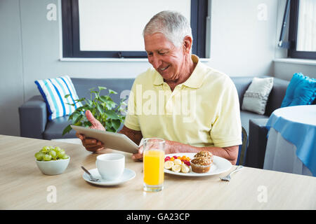 Senior uomo utilizzando una tavoletta digitale Foto Stock