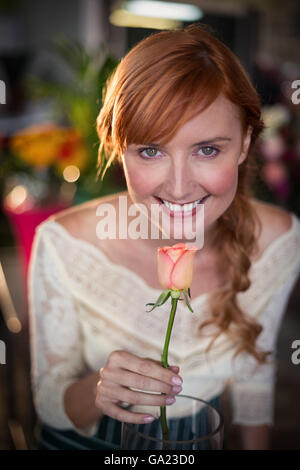 Ritratto di donna fioraio odorare un fiore rosa Foto Stock