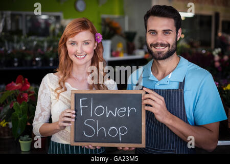 Ritratto di giovane azienda ardesia con negozio di fiori segno Foto Stock