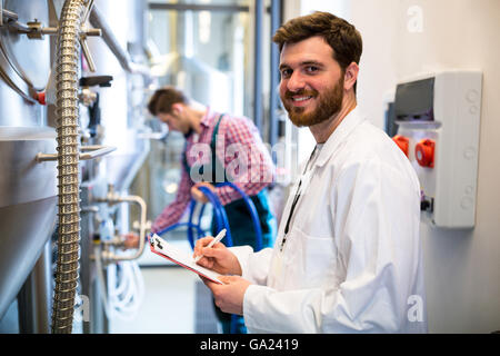 Lavoratori di manutenzione esaminando brewery macchina Foto Stock