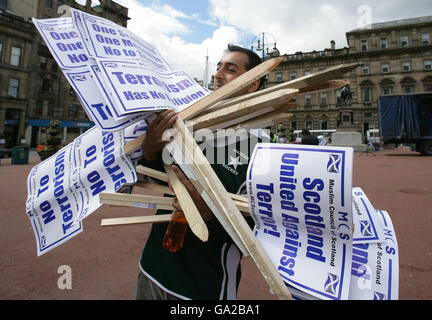 Un dimostratore porta cartelli per la Scozia unita contro il Terrore raduno a Glasgow. Foto Stock