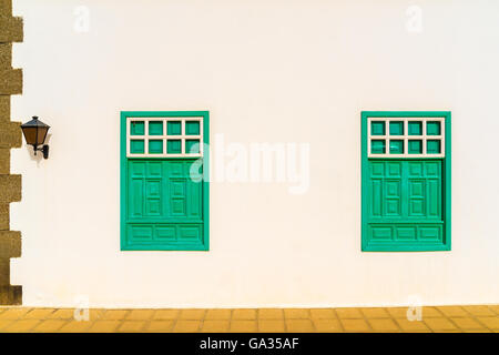 Facciata bianca della casa tipica con verde di Windows nel villaggio di Yaiza, Lanzarote, Isole Canarie, Spagna Foto Stock