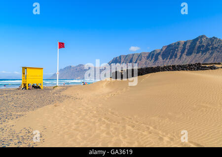 Dune di sabbia e giallo stand bagnino sulla spiaggia di Famara, famoso luogo di surf sulla isola di Lanzarote, Spagna Foto Stock