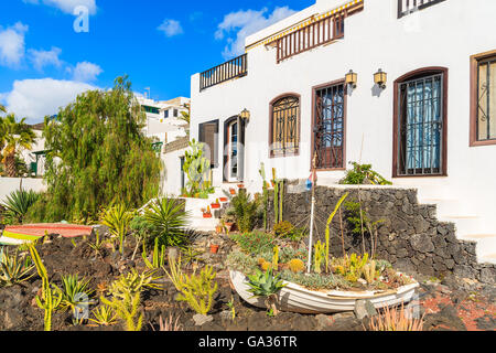 Barca da pesca nel giardino della tipica canaria case in Puerto del Carmen città sulla costa dell'isola di Lanzarote, Spagna Foto Stock