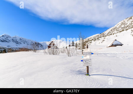 Sentiero di montagna segno sepolto nella neve in valle Gasienicowa con capanne in distanza, Monti Tatra, Polonia Foto Stock