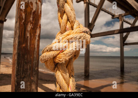 In prossimità di una spessa di colore arancio annodato la corda appesa da un molo su una spiaggia in Hartlepool nel nord est dell' Inghilterra Foto Stock