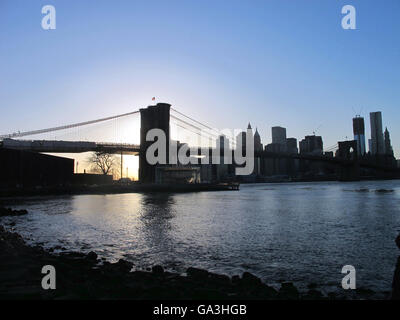 Il tramonto dalla East River e il Ponte di Brooklyn con inferiore dello skyline di Manhattan all'orizzonte. Foto Stock