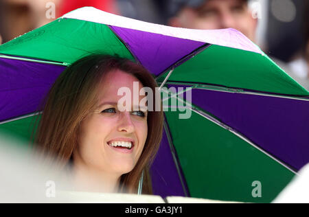 Kim Murray ripari sotto un ombrello come la pioggia smette di giocare sul Centre Court il giorno sei dei campionati di Wimbledon al All England Lawn Tennis e Croquet Club, Wimbledon. Foto Stock