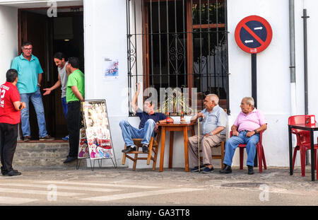 Uomini locale del villaggio di Grazalema avente conversazione davanti al bar in terrazza. Andalusia, Spagna. Foto Stock