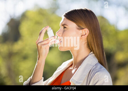 Donna che utilizza l'asma inalatore Foto Stock