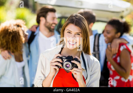 Bella donna facendo clic su una foto dalla fotocamera in posizione di parcheggio Foto Stock