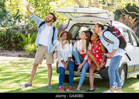 Gruppo di amici prendendo un selfie dal tronco di auto Foto Stock