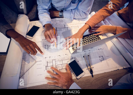 Quattro architetti discutendo blueprint in riunione Foto Stock
