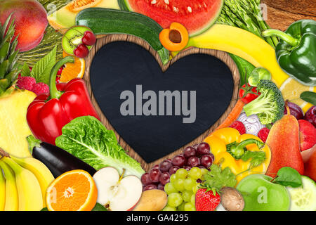 A forma di cuore ad telaio fuori della frutta e della verdura su sfondo di ardesia Foto Stock