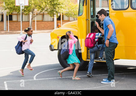 Docente dando alta cinque per i bambini mentre entrando in autobus Foto Stock