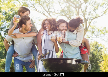 Gli uomini dando sovrapponibile alle donne durante la preparazione di barbecue in posizione di parcheggio Foto Stock