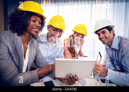 Architetti sorridente discutendo su tavoletta digitale in ufficio Foto Stock