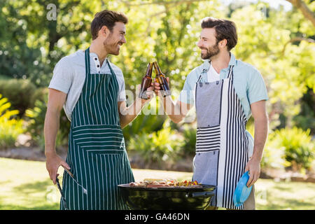 Gli uomini di tostatura bottiglia di birra mentre prepara barbecue grill Foto Stock