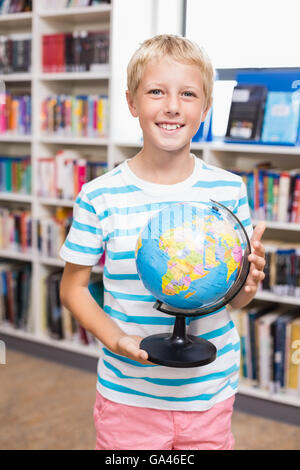 Scolaro holding globe in libreria Foto Stock