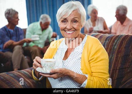 Sorridente donna senior in possesso di una tazza di caffè Foto Stock