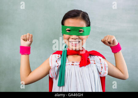 Felice ragazza vestita come supereroe in aula Foto Stock