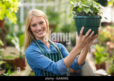 Ritratto di giovane donna appeso pianta in vaso Foto Stock