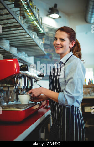 Ritratto di cameriera versando il caffè da espresso maker Foto Stock