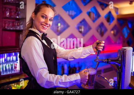 Ritratto di felice barista spillatura della birra in vetro Foto Stock